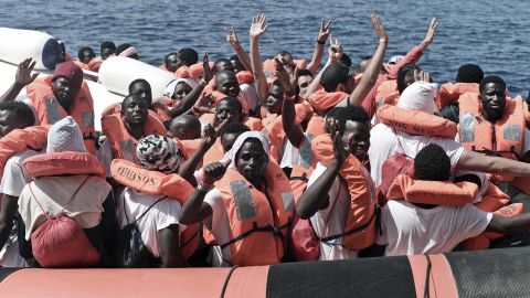 Migrants wave after being transferred from the Aquarius ship to Italian Coast Guard boats on June 13, 2018 in the Mediterranean Sea.