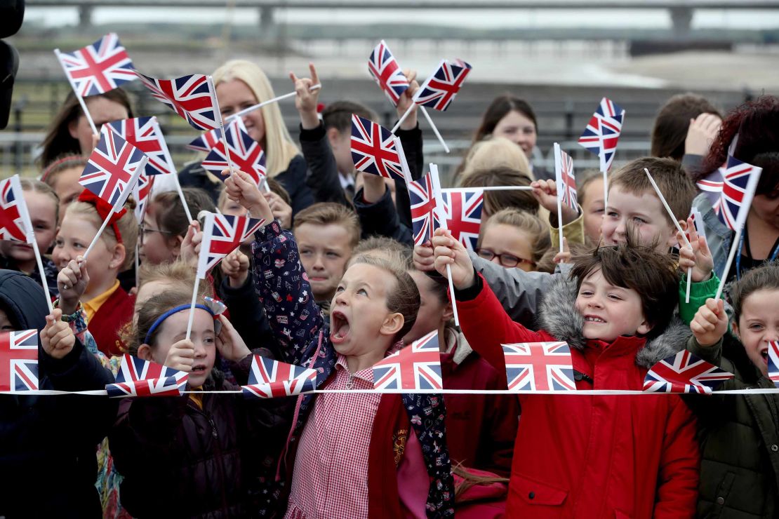 Schoolchildren near Runcorn Station wait to see the monarch and new royal arrive in the Cheshire town to open a new toll bridge nearby.