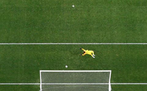 The ball flies past Saudi Arabian goalkeeper Abdullah Al-Mayouf for Russia's fourth goal.