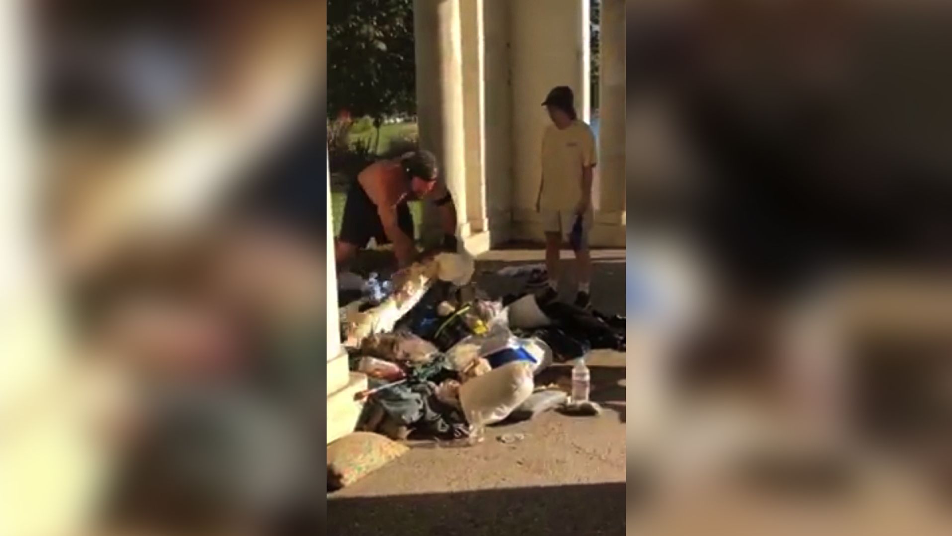 A  jogger gathers a homeless man's possessions in his arms before throwing them into a trash can