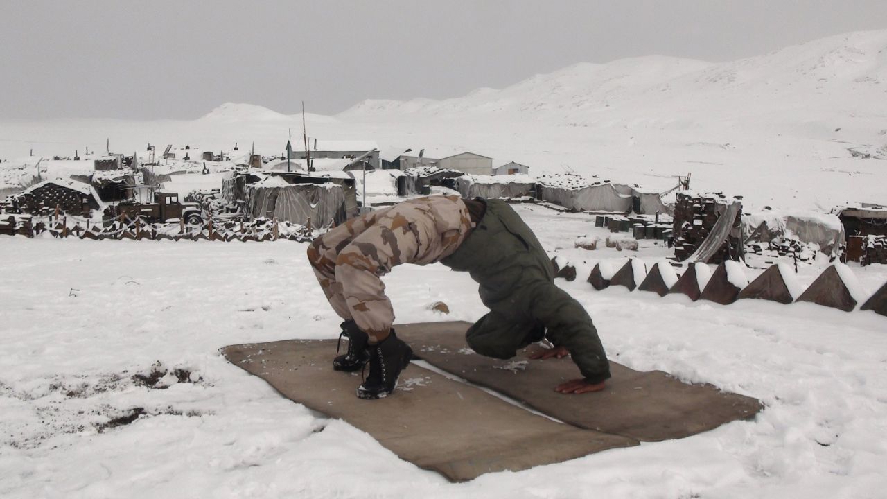 A member of the Indo-Tibetan Border Police practice wheel pose at a military base in the Himalayan mountains.