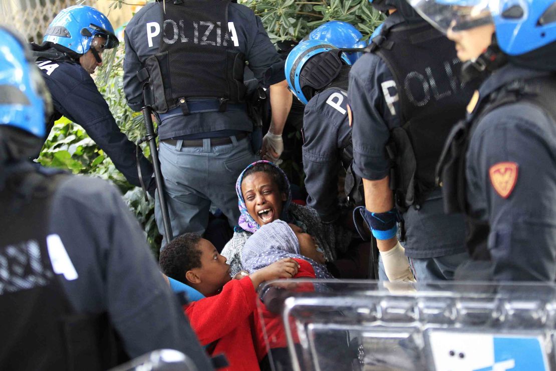 Italian police officers surround a family of migrants during an operation to remove them from the Italian-French border in the Italian city of Ventimiglia on June, 16, 2015.  