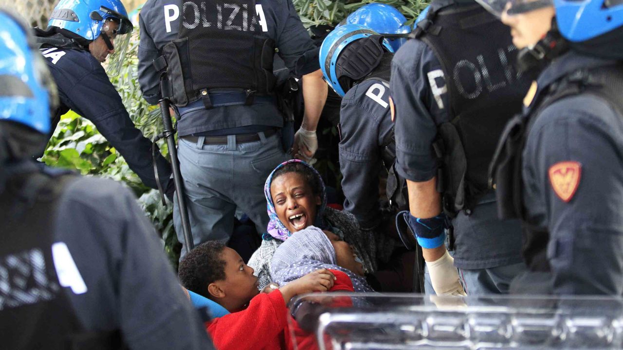 Italian police officers surround a family of migrants during an operation to remove them from the Italian-French border in the Italian city of Ventimiglia on June, 16, 2015.