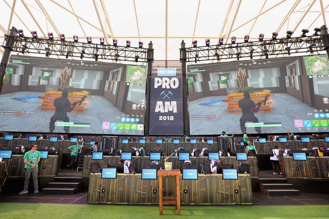 The Fortnite trophy is displayed in the foreground as gamers compete in Epic Games' Fortnite E3 Tournament. 