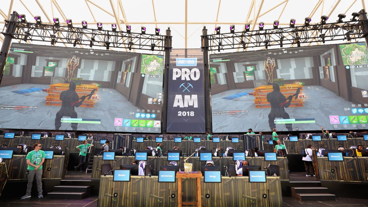 The Fortnite trophy is displayed in the foreground as gamers compete in Epic Games' Fortnite E3 Tournament. 