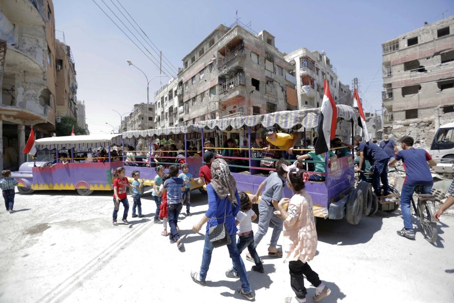 People ride a "fun train" on the war-damaged streets of Douma, Syria.