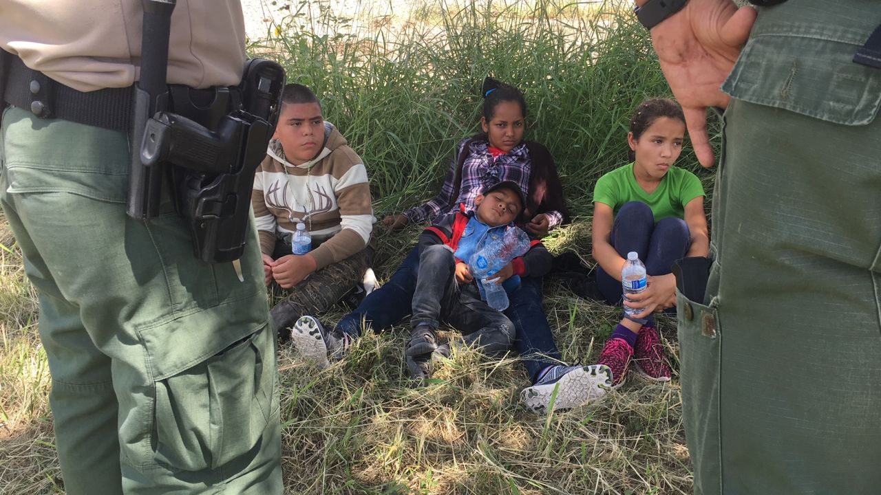 Dalila Suyapa and her son Cesar (center) take a break from the sun after Border Patrol agents took them in custody in Mission, Texas on Friday.