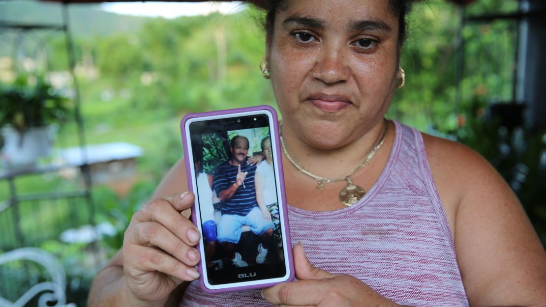 Lisa De Jesús holds a picture of her deceased friend, "Rey Bruquena," or "Rey Crab," who earned that nickname because of his love for the ocean.