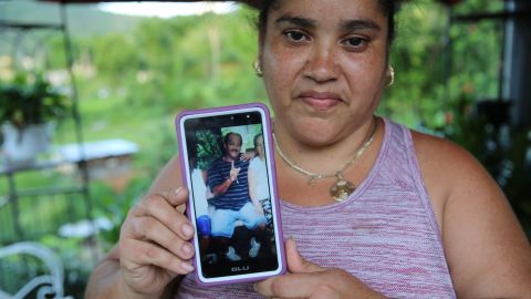 Lisa De Jesús holds a picture of her deceased friend, "Rey Bruquena," or "Rey Crab," who earned that nickname because of his love for the ocean.