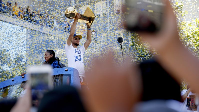 Stephen Curry of the Golden State Warriors holds the Larry O'Brien Championship Trophy during a parade in downtown Oakland on Tuesday, June 12. The Warriors have won back-to-back NBA titles, and this is their third title in four years.