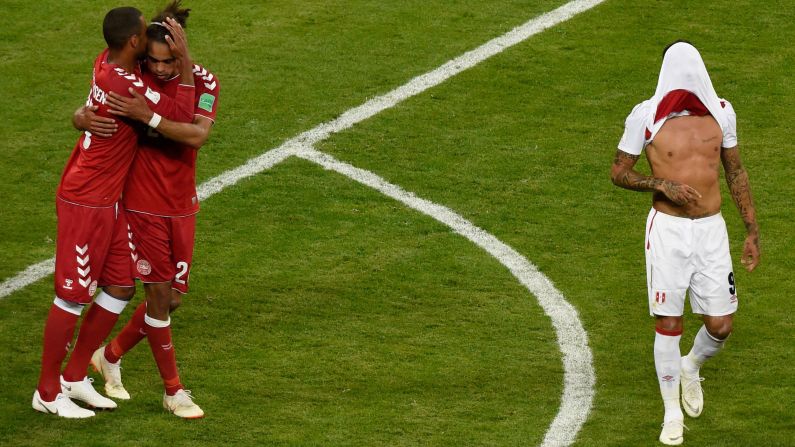Peru's forward Paolo Guerrero walks with his shirt over his face as two members of Denmark's team celebrate after the football match between Peru and Denmark on Saturday, June 16. Denmark defeated Peru 1-0.