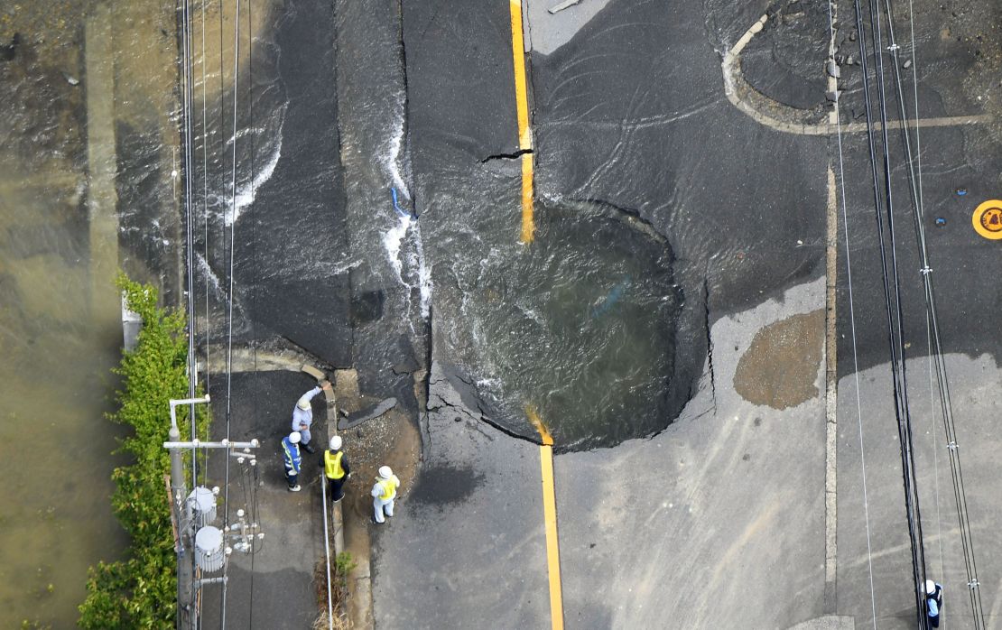 Water floods out from a crack in the road, following the Osaka quake.