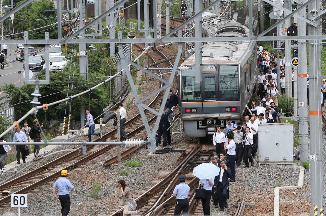 Passengers walk along railroad tracks after the earthquake.