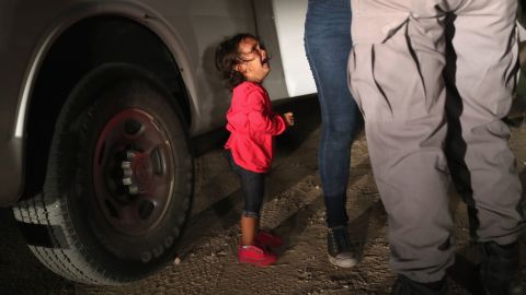 A two-year-old Honduran asylum seeker cries as her mother is searched and detained near the U.S.-Mexico border.