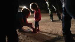 MCALLEN, TX - JUNE 12:  A Honduran mother removes her two-year-old daughter's shoe laces, as required by U.S. Border Patrol agents, after being detained near the U.S.-Mexico border on June 12, 2018 in McAllen, Texas. The asylum seekers had rafted across the Rio Grande from Mexico and were detained by federal authorities before being sent to a processing center for possible separation. Customs and Border Protection (CBP) is executing the Trump administration's "zero tolerance" policy towards undocumented immigrants. U.S. Attorney General Jeff Sessions also said that domestic and gang violence in immigrants' country of origin would no longer qualify them for political asylum status.  (Photo by John Moore/Getty Images)