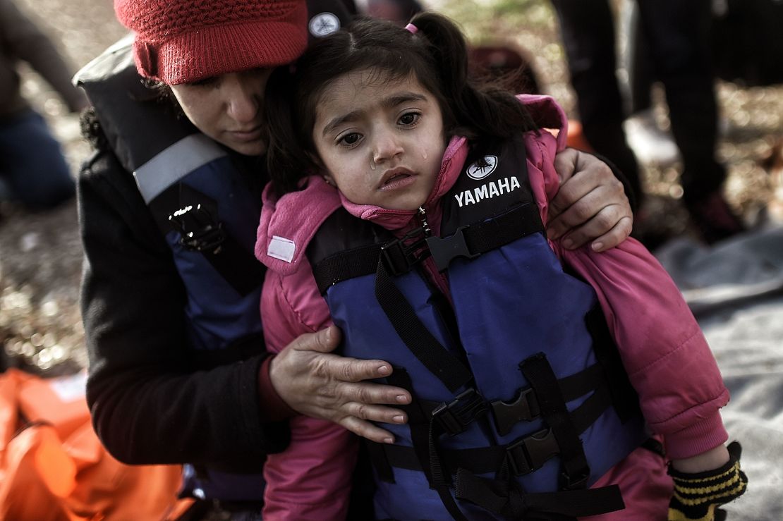 A woman hugs a young child as they arrive with other migrants on Lesbos in 2016. 