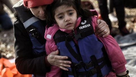 A woman hugs a young child as they arrive with other migrants on Lesbos in 2016. 