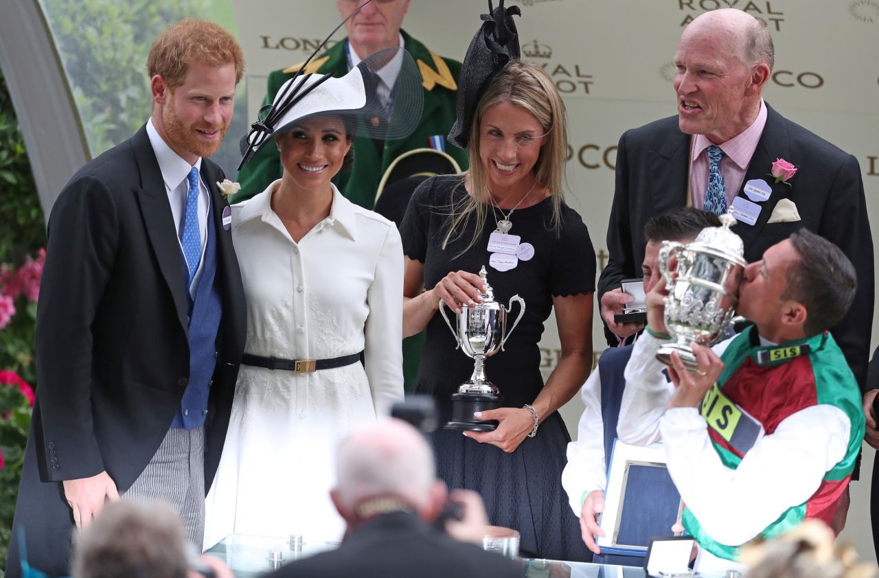Prince Harry and Meghan present a trophy to jockey Frankie Dettori for his winning ride on Without Parole as trainer John Gosden (right) watches on.