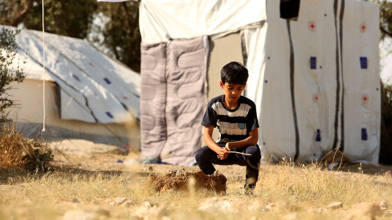 MYTILENE, GREECE - MAY 20: A refugee child plays alone at the Moria refugee camp on May 20, 2018 in Mytilene, Greece. Despite being built to hold only 2,500 people, the camp on the Greek island of Lesbos is home to over 6,000 asylum seekers who crossed the Aegean Sea from Turkey's nearby shore by boat, usually at night to avoid interception. Although the numbers of arrivals are lower than at the beginning of the crisis in 2015, when Syrians and Iraqis fled ISIS-controlled strongholds, boatloads of refugees from those countries and other troubled areas continue to land there, and critics say the local governments have yet to manage the situation, leading the squalid conditions at Moria to be seen as symbolic of poorly-managed policy. The camp, on the site of a former military base, is comprised of shipping containers, tents, and improvised shelters of wooden pallets and tarps, whose residents stranded there complain of poor food, power failures, disease, lack of medical care, and poisonous snakes as they wait to obtain transfer to the mainland and less temporary legal status.  (Photo by Adam Berry/Getty Images)