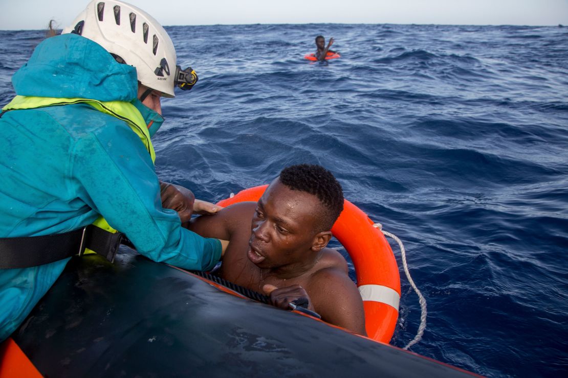 A member of Sea-Watch helps a migrant to board a boat after he was recovered in the Mediterranean on November 6, 2017. Five people died during the shipwreck.