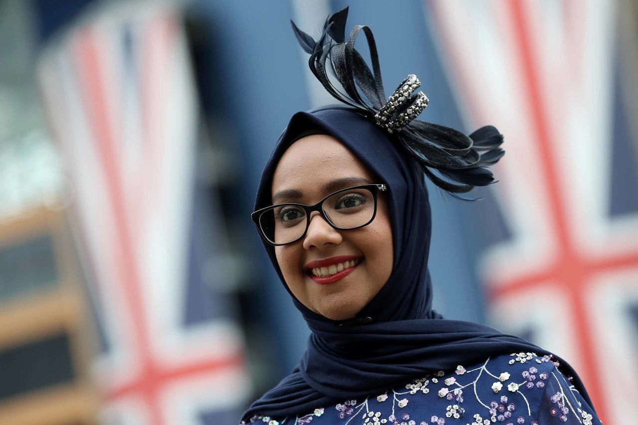 A young woman accessorizes her hijab with a fascinator. 