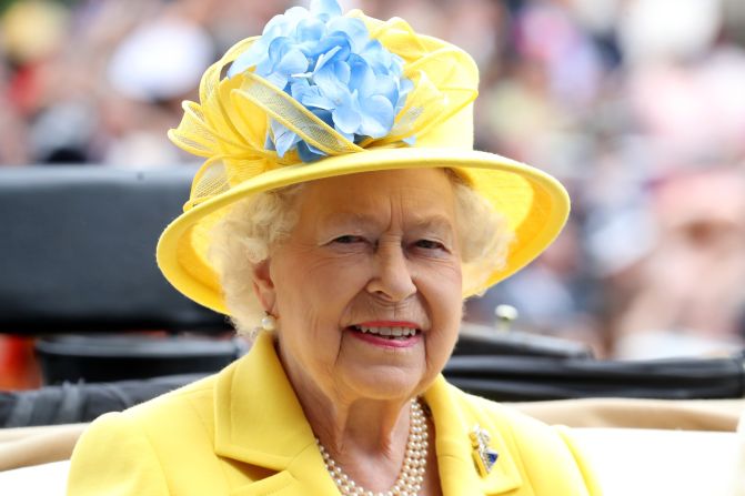 The Queen arrives by carriage to Royal Ascot Day wearing a bright yellow hat, with a flourish of blue.