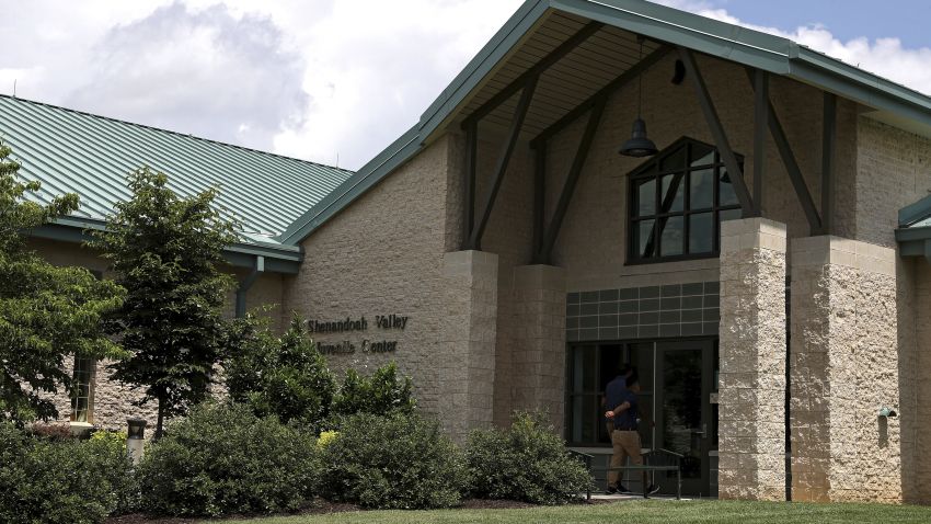A person walks into the entrance of the Shenandoah Valley Juvenile Center on Wednesday, June 20, 2018 in Staunton, Va. Immigrant children as young as 14 housed at the juvenile detention center say they were beaten while handcuffed and locked up for long periods in solitary confinement, left nude and shivering in concrete cells. The abuse claims are detailed in federal court filings that include a half-dozen sworn statements from Latino teens jailed there for months or years. (AP Photo/Zachary Wajsgras)