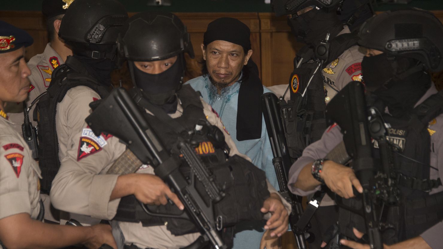 Indonesian anti-terror police officers escort Aman Abdurrahman after the judges' verdict.