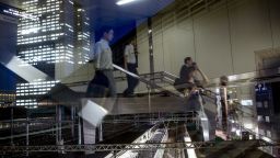 TOKYO, JAPAN - JULY 22: Office workers are seen reflected in a window as they walk to a train station in front of the  Toshiba Corporations, Tokyo headquarters (left) on July 22, 2015 in Tokyo, Japan. Toshiba Corporation President Hisao Tanaka and two other executives resigned July 21, over a $1.2billion accounting scandal.  (Photo by Chris McGrath/Getty Images)