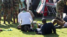 Injured people are attended to as they lay on the ground following an explosion at a Zanu pf rally in Bulawayo, Saturday, June, 23, 2018.  An explosion rocked a stadium where Zimbabwe's president was addressing a campaign rally on Saturday, with state media calling it an assassination attempt but saying he was not hurt and was evacuated from the scene. Witnesses said several people were injured, including a vice president. (AP Photo)