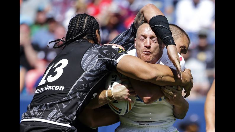England rugby player James Roby, in white, is held back by New Zealand's Martin Taupau on Saturday, June 23, in Denver.