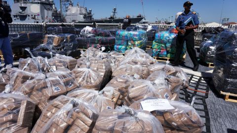 Coast Guard personnel stand aboard the USS Boutwell while officials unload bails of cocaine caught at sea while on deployment in 2015 at Naval Base San Diego, California.  