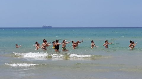 Beachgoers enjoy a Zumba class in Pozzallo, Sicily, as the Maersk migrant ship sits in the background.