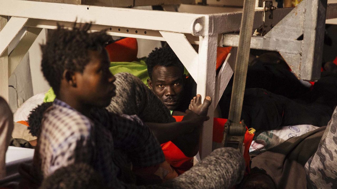Rescued migrants sit in the search and rescue ship Lifeline as the boat remained stranded Monday.