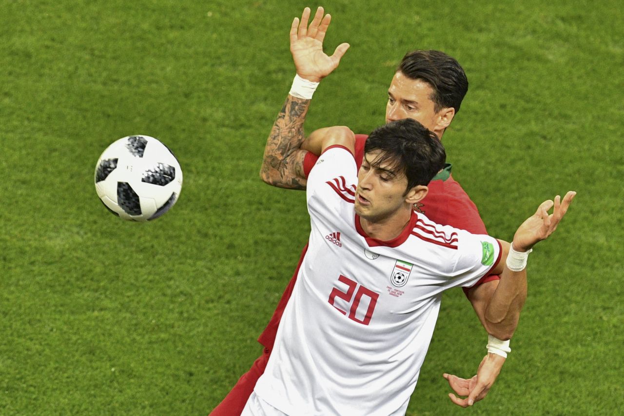 Iranian forward Sardar Azmoun shields the ball from Portuguese defender Jose Fonte.