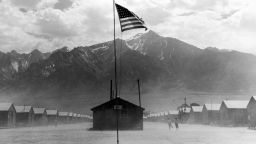 CALIFORNIA, UNITED STATES - FEBRUARY 02:  Incongruous American flag flying over scene of two children running on dusty wind swept grounds of bleak Manzanar relocation camp, one of several such camps housing forcebly relocated Japanese nationals and American citizens of Japanese descent during WW  