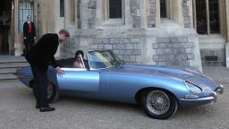 Britain's Prince Harry, Duke of Sussex, (L) opens the passenger door of an E-Type Jaguar car for his wife Meghan Markle, Duchess of Sussex, (R) as they leave Windsor Castle in Windsor on May 19, 2018 after their wedding to attend an evening reception at Frogmore House. (Photo by Steve Parsons / POOL / AFP)        (Photo credit should read STEVE PARSONS/AFP/Getty Images)