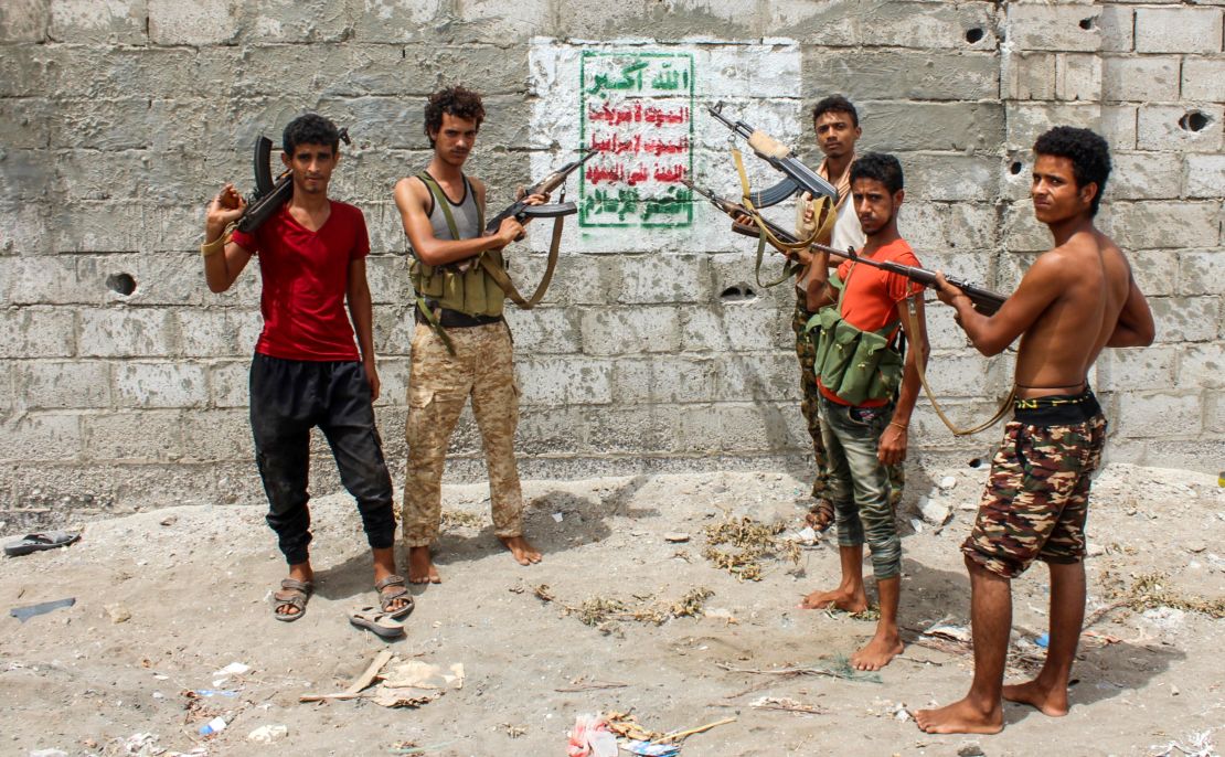 Fighters loyal to the Saudi-backed government point rifles toward a Houthi banner on the outskirts of Hodeidah. 