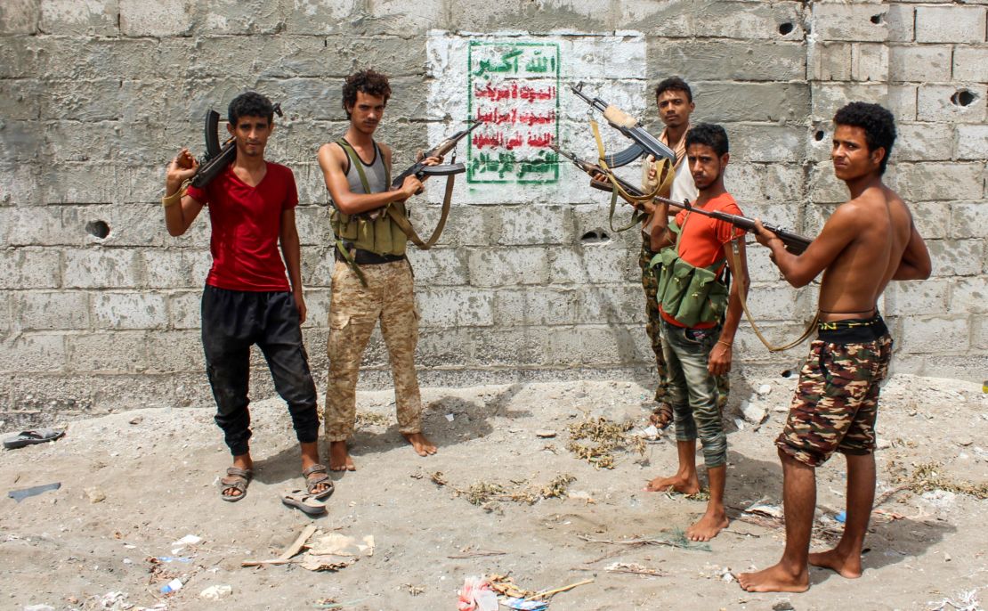 Fighters loyal to the Saudi-backed government point rifles toward a Houthi banner on the outskirts of Hodeidah.