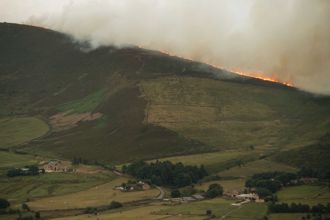 A large moorland wildfire burns on the hills above Dove Stone Reservoir near Stalybridge, northwest England.