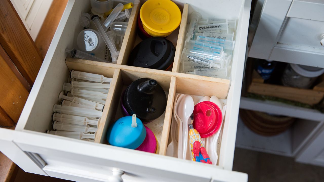 A kitchen drawer in the family home is full of syringes, next to spoons and sippy cups. 