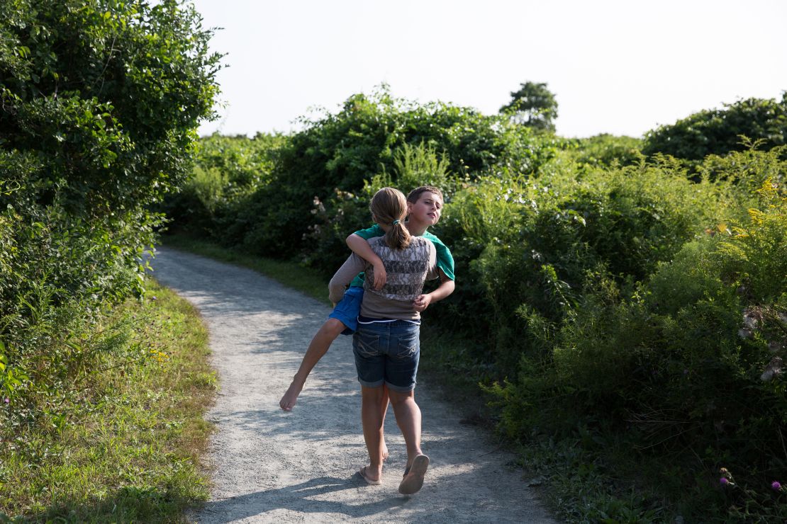 Bristel carries her brother along a path during a family outing. Despite his seizures, Trevor and his siblings still play and goof around like any other family.