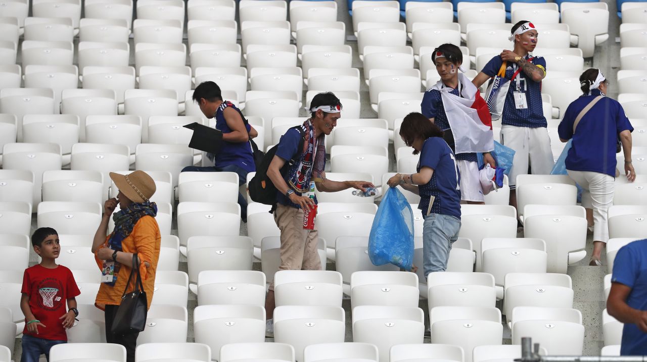 Japan supporters clear litter from the stands after the match.