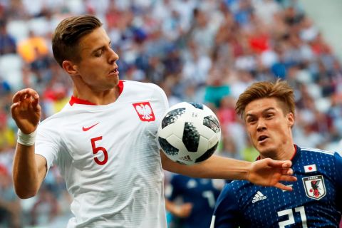 Poland's Jan Bednarek, left, competes for the ball with Japan's Gotoku Sakai on June 28. Poland won 1-0, but Japan advanced to the next round.