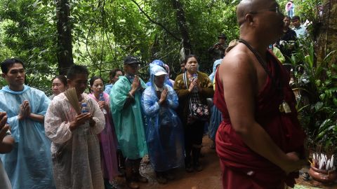 A Buddhist monk and relatives pray as they keep vigil near the Tham Luang cave.