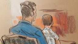 6-year-old boy, Rodolfo, the youngest  child in court this day, sits on his father's lap. As he did with most of the children, Judge Bryant asked Rodolfo if he was in school, translated by an interpreter via headphones provided to every immigrant facing the court.