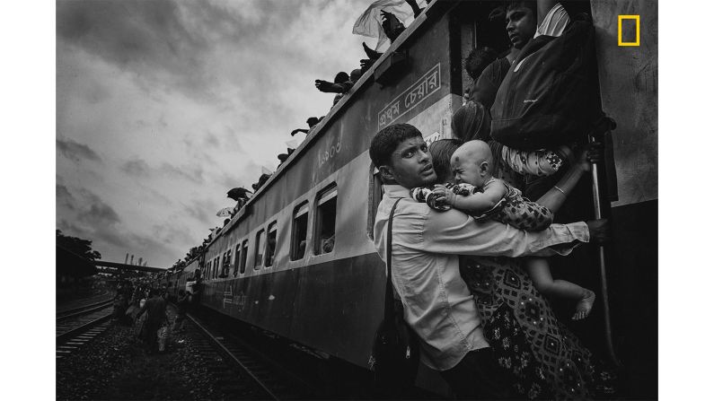 <strong>3rd prize People category -- "Challenging Journey":</strong> The third prize winner in the people category of the<a href="http://travel.nationalgeographic.com/photographer-of-the-year-2018/gallery/winners-all/1/" target="_blank" target="_blank"> 2018 National Geographic Travel Photographer of the Year Contest</a> is <a href="http://yourshot.nationalgeographic.com/profile/190415/" target="_blank" target="_blank">MD Tanveer Hassan Rohan</a>, who took this photograph of Dhaka's airport rail station during the Eid vacation. "One man caught my attention: he was dangling on a train's handle with his family, trying to get inside the train. At that time, rain started and the train began to slowly move," says the photographer.