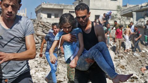 A man carries a child rescued from rubble after Syrian regime and Russian air strikes in the rebel-held town of Nawa, on June 26, 2018. 
