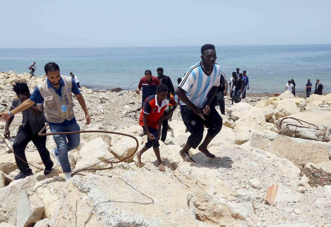 Migrants who survived the sinking climb the rocky shore of al-Hmidiya, east of the capital Tripoli.