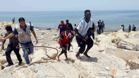 Migrants who survived the sinking climb the rocky shore of al-Hmidiya, east of the capital Tripoli.